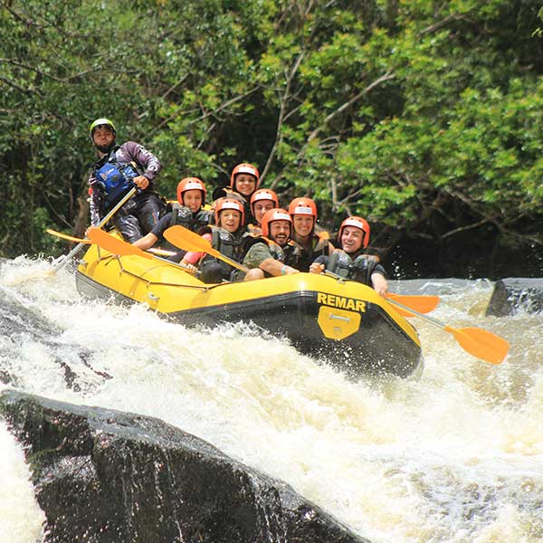 Bote da Brotas rafting com sete pessoas sentadas no piso do bote descendo uma queda