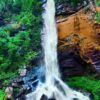 Cachoeira-da-figueira. A-lateral-esquerda-é-repleta-de-verde-e-o-lado-direito-um-paredão-rochoso.