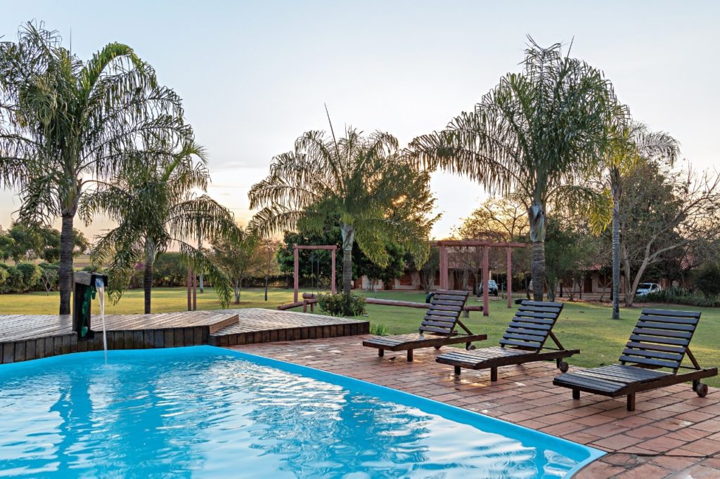 piscina-com-espreguiçadeiras-na-lateral-ao-fundo-o-parquinho-de-madeira-para-crianças
